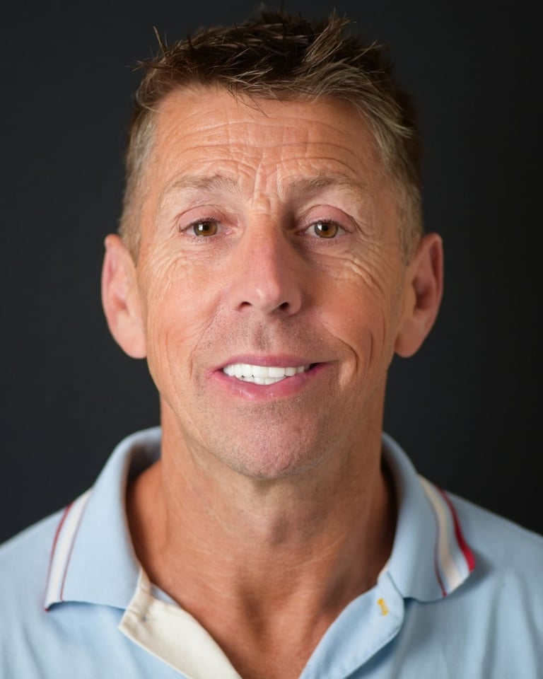 Portrait of a man with short brown hair wearing a light blue polo shirt with white collar and red accents, smiling gently and showing straight white teeth after dental restoration at Smile Center Turkey.