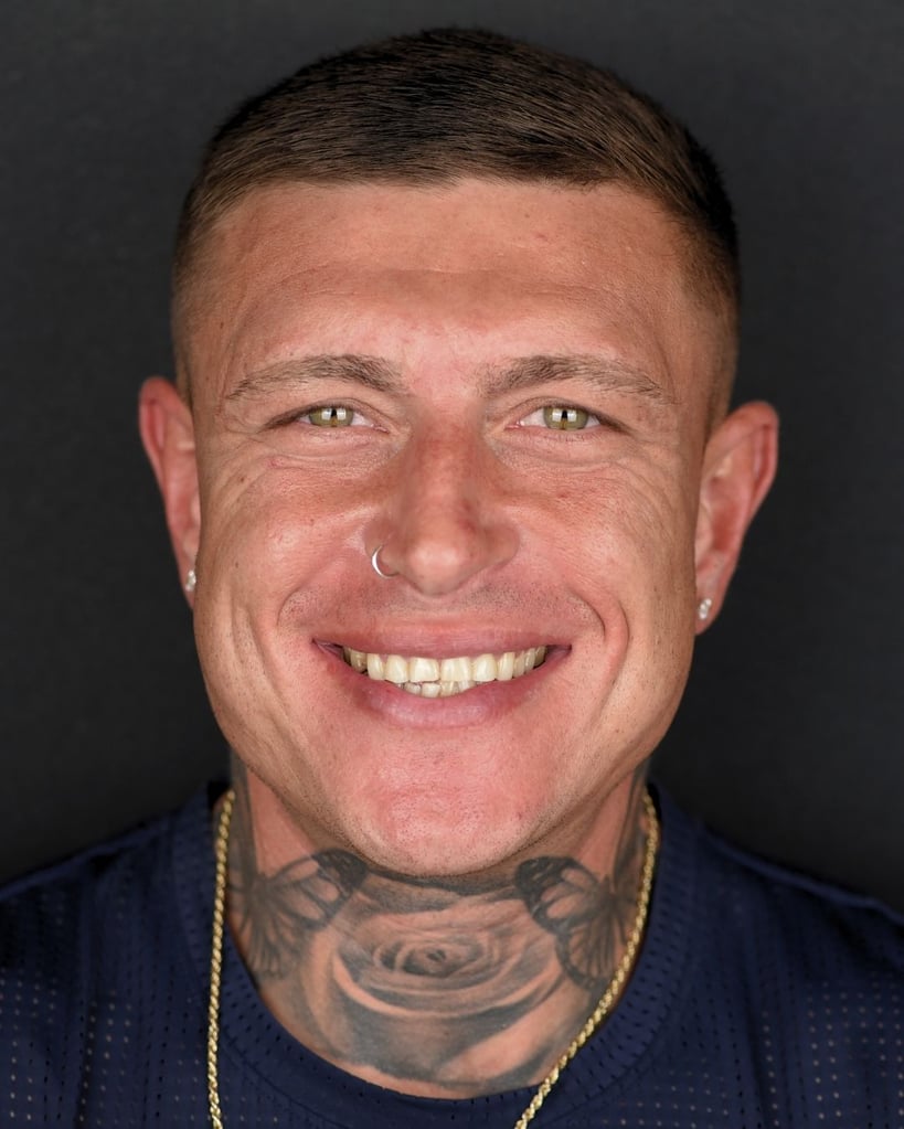 Close-up portrait of a smiling man with a tattooed neck and a nose ring at Smile Center Turkey.