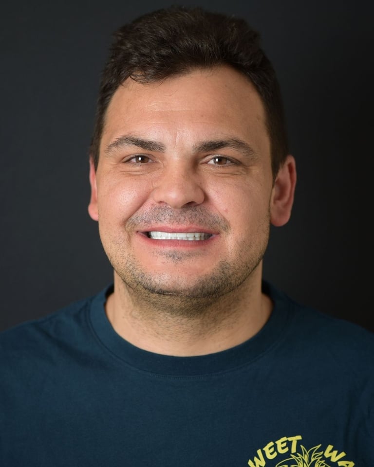 Portrait of a man with short dark hair wearing a navy blue T-shirt with yellow design, smiling gently and showing straight white teeth after dental restoration at Smile Center Turkey.