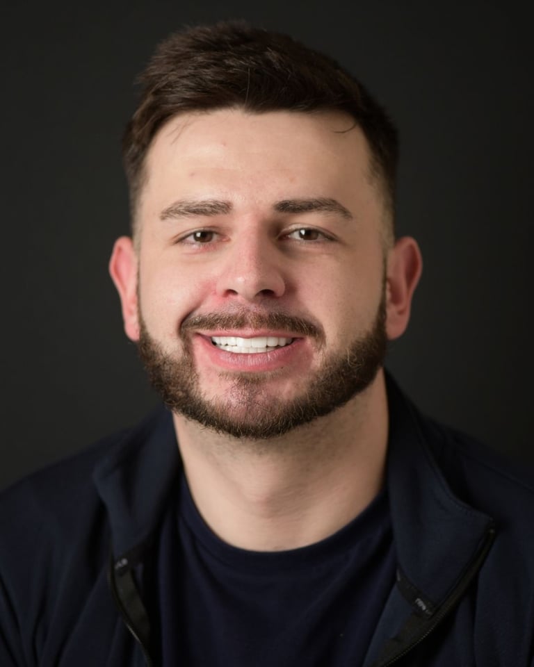 Portrait of a man with short dark brown hair and a trimmed beard, wearing a dark blue jacket, smiling broadly and showing bright white teeth after dental restoration at Smile Center Turkey.