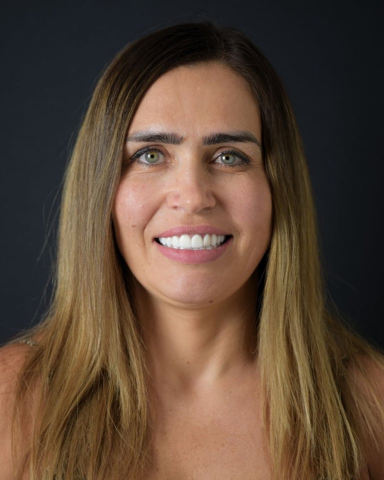 Portrait of a woman with long brown hair and green eyes, wearing a sleeveless top, smiling gently and showing straight white teeth after dental restoration at Smile Center Turkey.