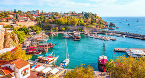 Colourful boats in Antalya's Kaleici harbour with historic city walls and blue Mediterranean Sea