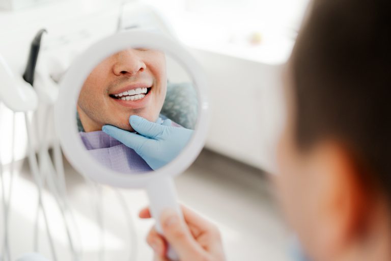 UK patient dental treatment in Turkey – smiling man holding mirror at Smile Center Turkey (dental tourism guide)